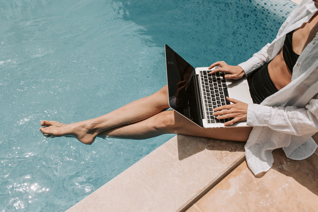 Woman Sitting on Poolside Using Laptop